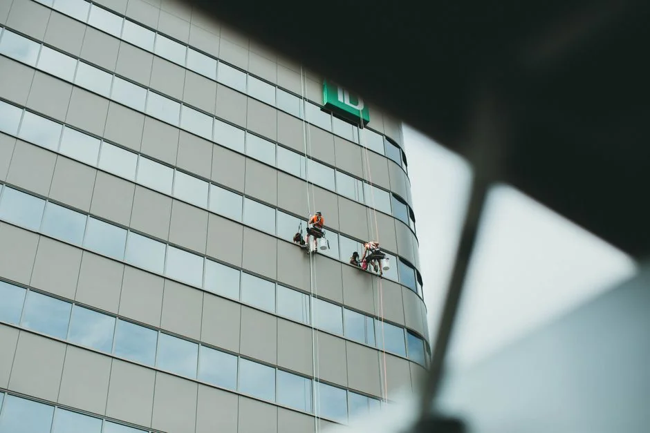 An adult male cleaning a glass window indoors, focusing on household chores and cleanliness.